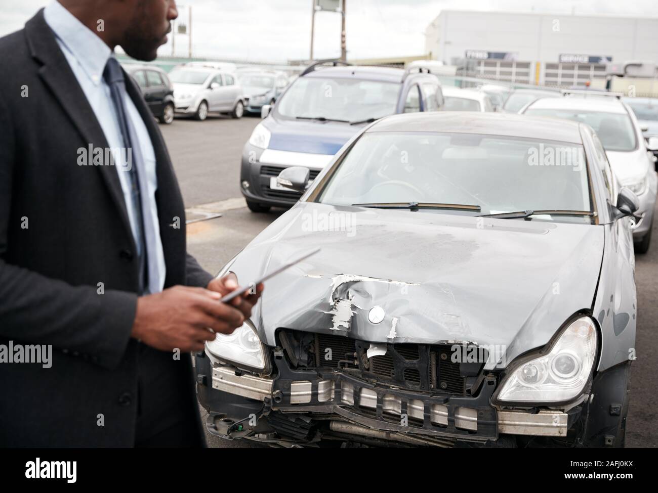 Männliche Insurance Loss Adjuster mit digitalen Tablet Inspektion Schaden an dem Auto von Motor Unfall Stockfoto