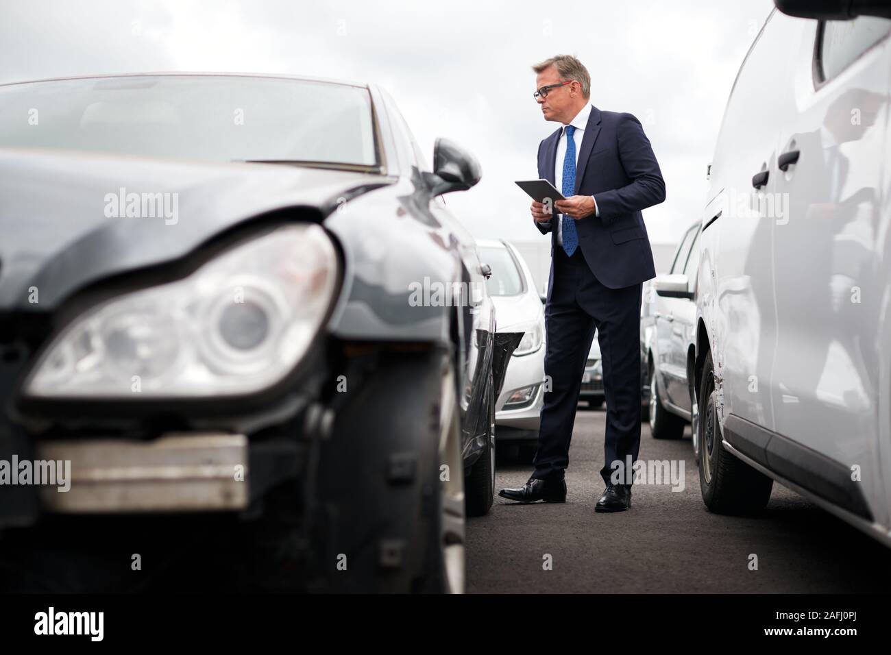 Männliche Insurance Loss Adjuster mit digitalen Tablet Inspektion Schaden an dem Auto von Motor Unfall Stockfoto