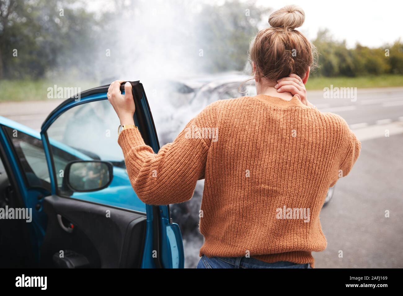 Ansicht der Rückseite des Weiblichen Kraftfahrer mit Kopfverletzung Aussteigen aus dem Auto nach einem Crash Stockfoto