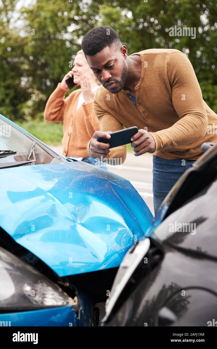 Männliche Autofahrer bei Autounfall, der Schaden für die Versicherung verwickelt Stockfoto
