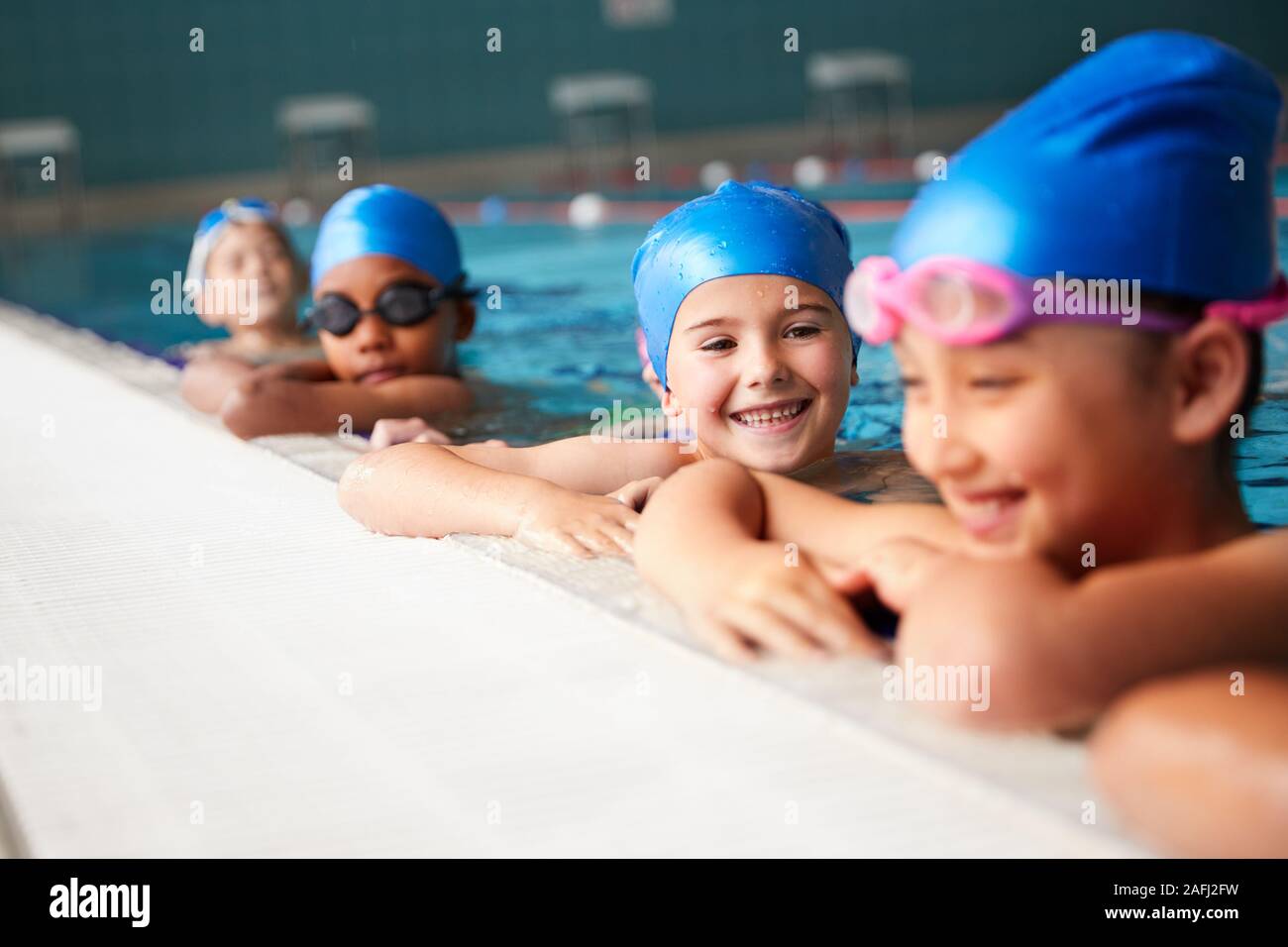 Gruppe von Kindern im Wasser am Rand des Pool warten auf Schwimmunterricht Stockfoto