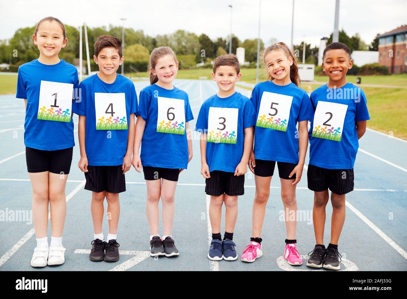 Portrait von Kindern auf der Leichtathletikbahn tragen Wettbewerber Zahlen auf Sport Tag Stockfoto