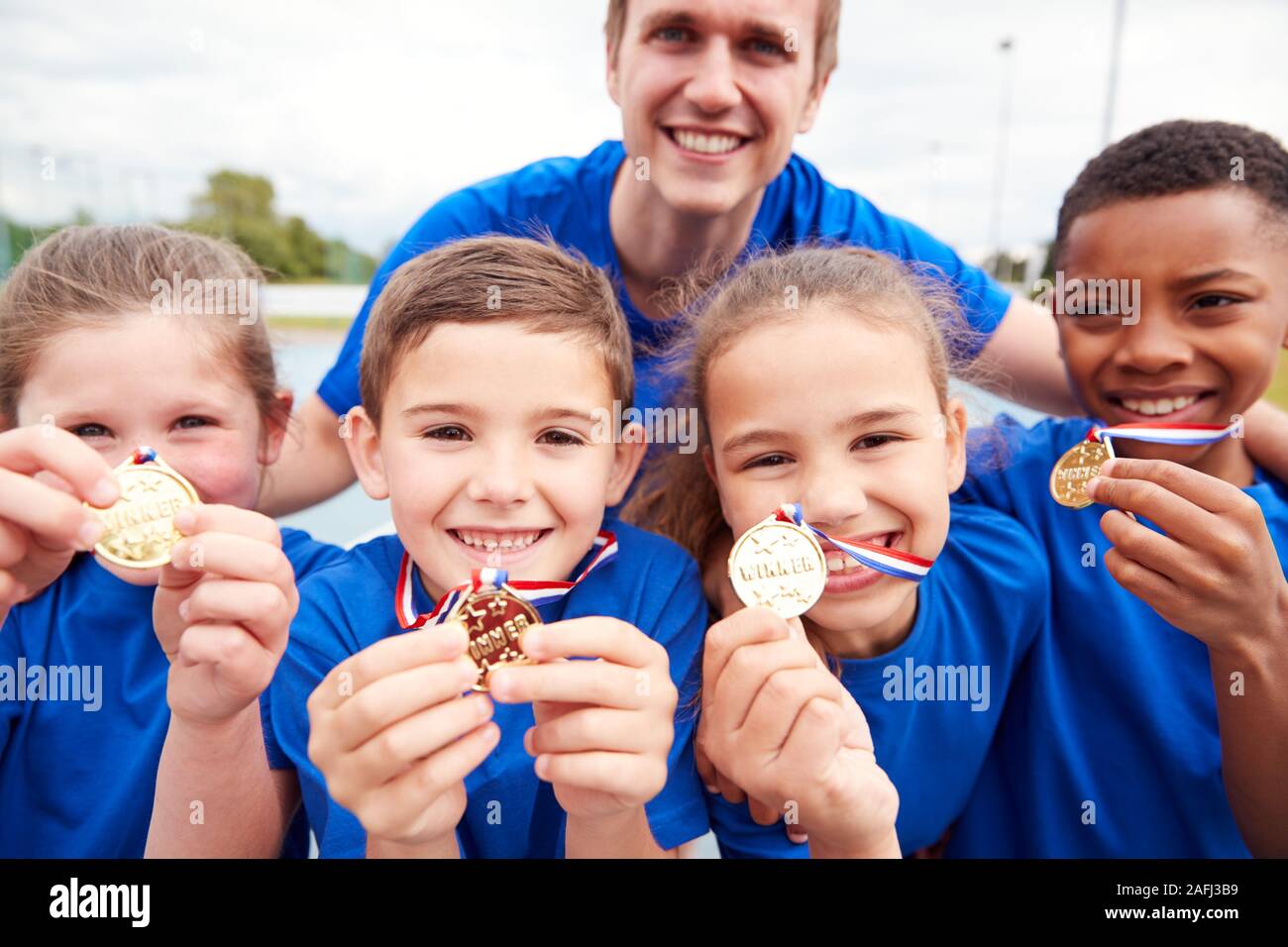 Portrait von Kindern mit männlichen Trainer zeigen, ein Sieger Medaillen auf Sport Tag Stockfoto