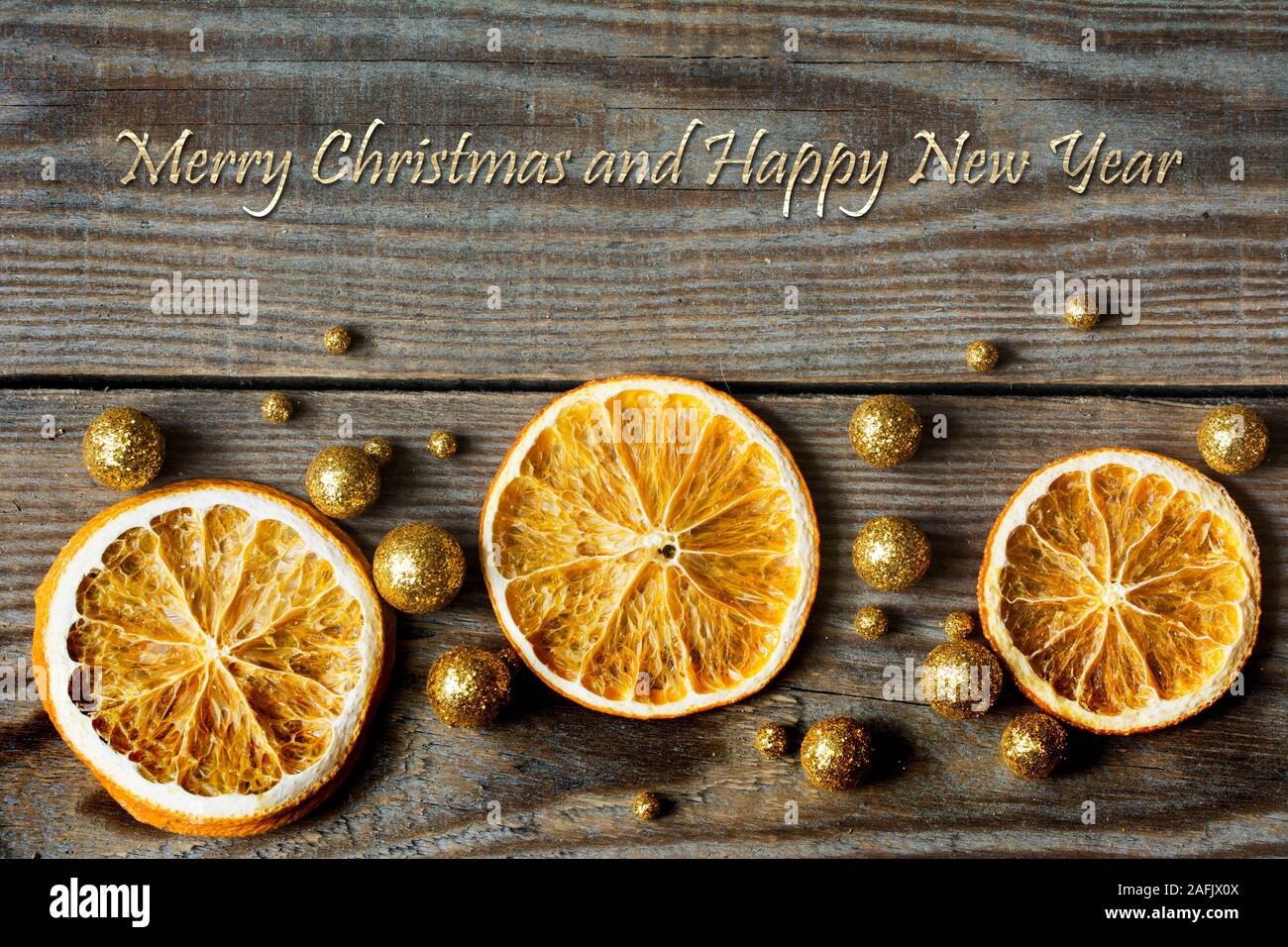 Weihnachten Zusammensetzung mit getrockneten Orangen und golden glitter Kugeln auf Holz- Hintergrund - close-up, Grüße Stockfoto