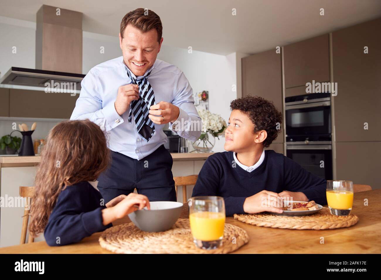 Kinder essen Frühstück vor der Schule als Vater machen Sie sich bereit für die Arbeit im Büro Stockfoto