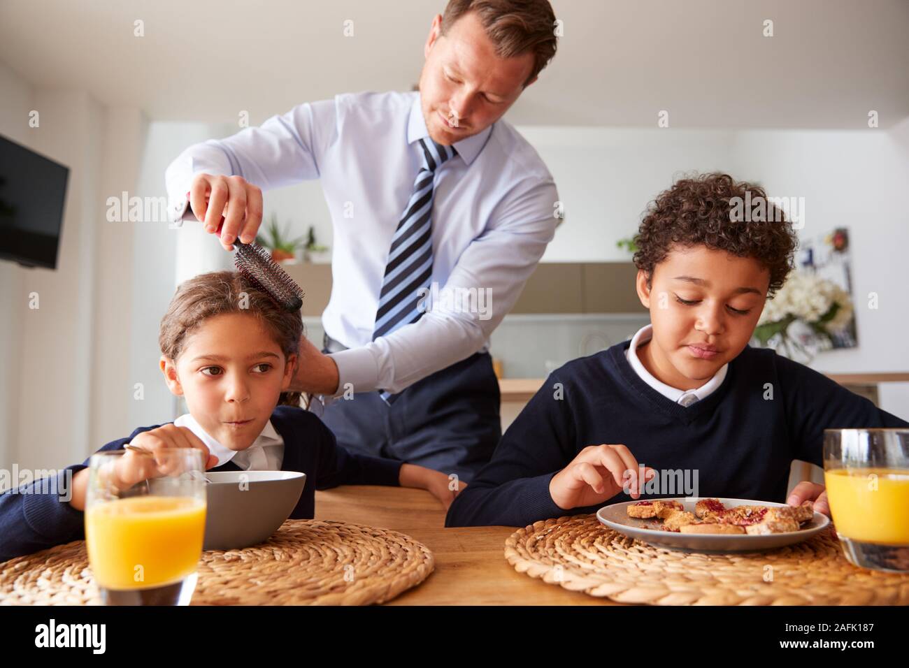 Geschäftsmann Vater in der Küche putzen Haar und Helfen, Kinder mit Frühstück vor der Schule Stockfoto