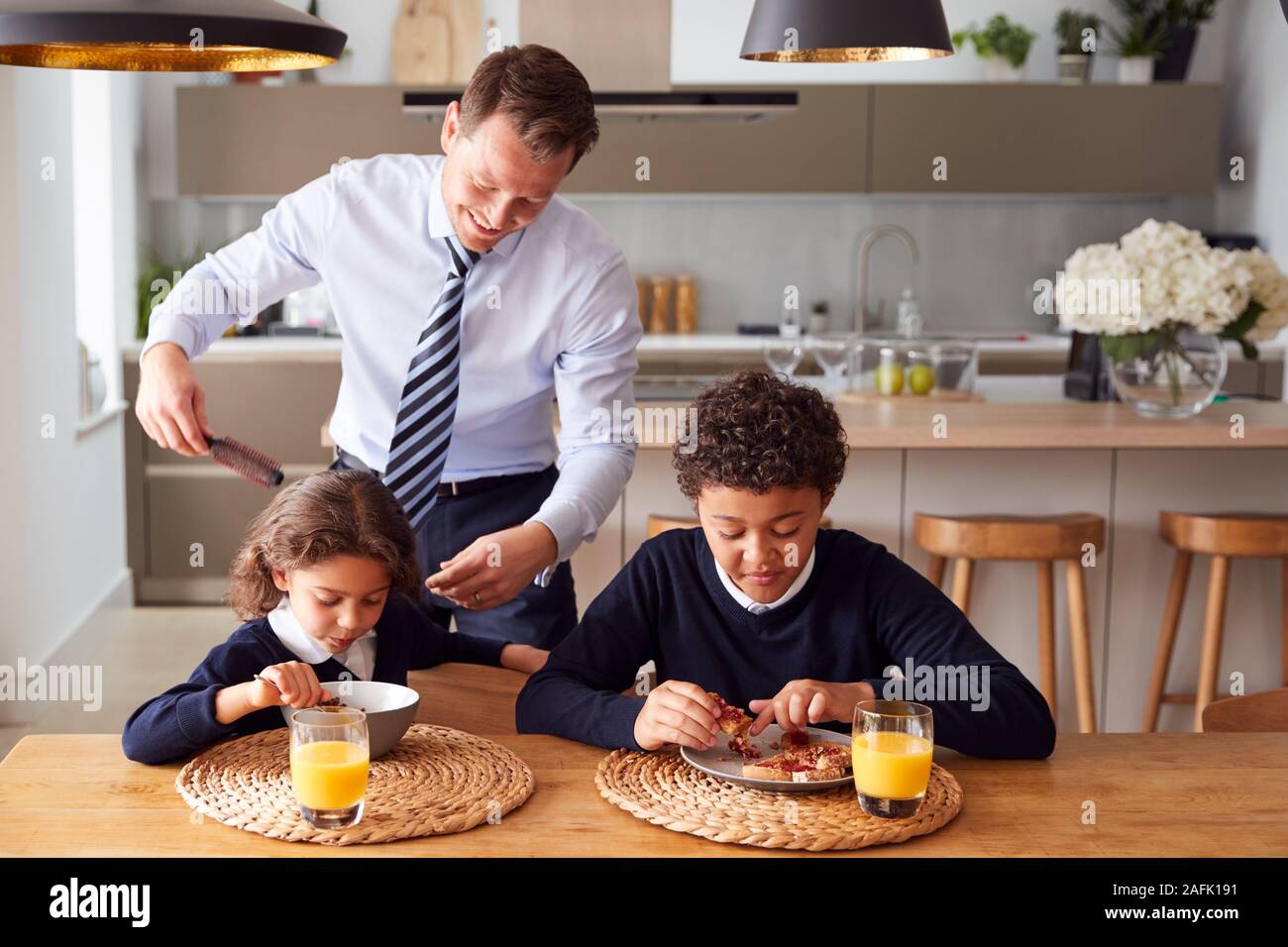 Geschäftsmann Vater in der Küche putzen Haar und Helfen, Kinder mit Frühstück vor der Schule Stockfoto