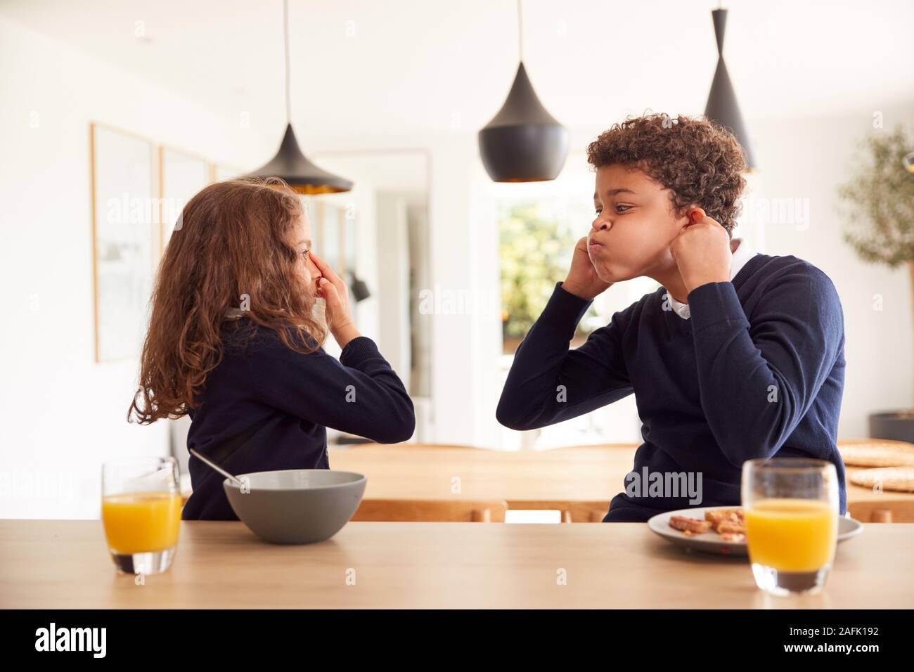 Kinder In der Küche essen Frühstück und Grimassen, bevor sie in die Schule gehen Stockfoto