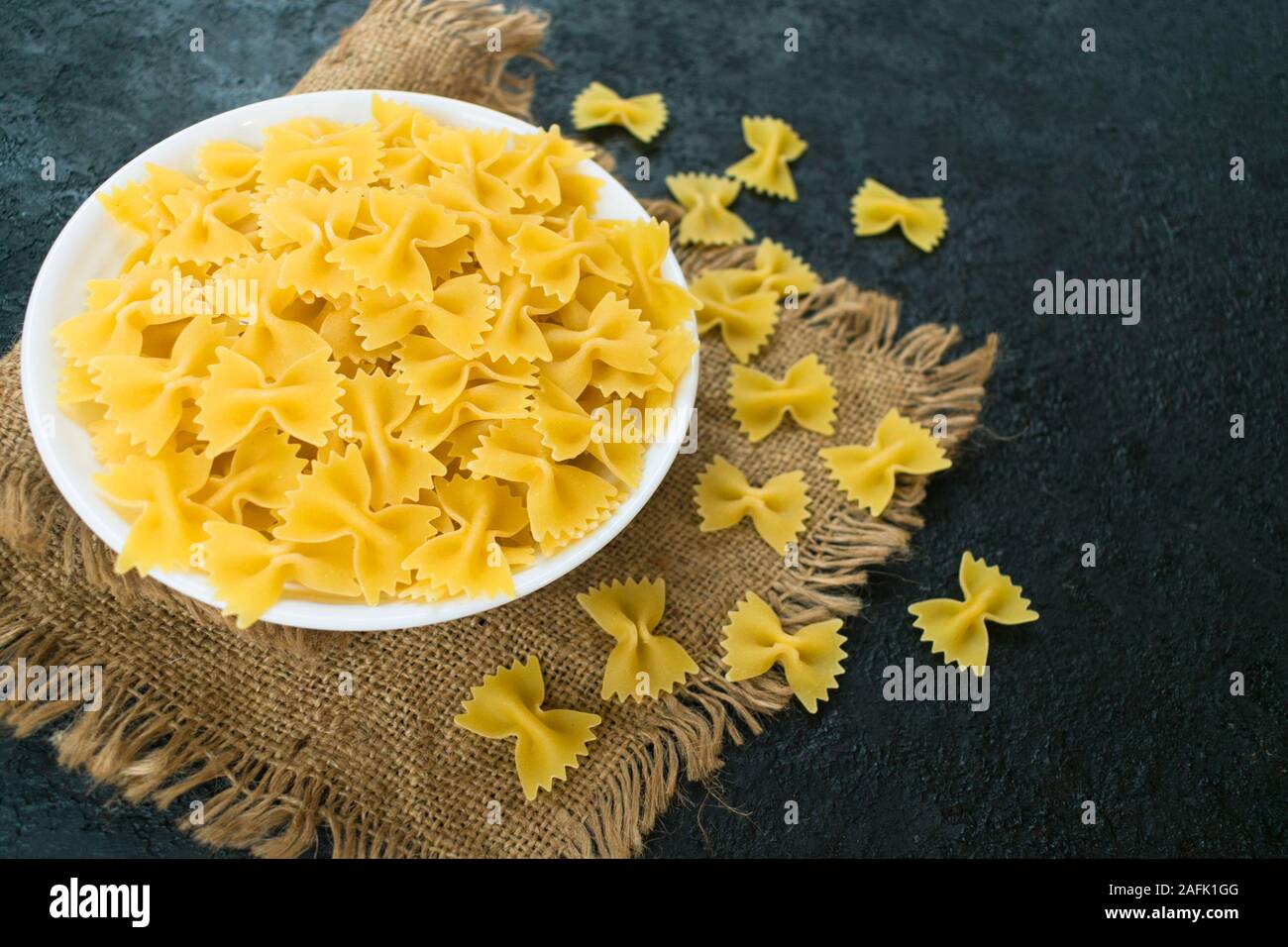Nudeln in der Form eines Bogen in eine Platte auf einem schwarzen Hintergrund. Stockfoto