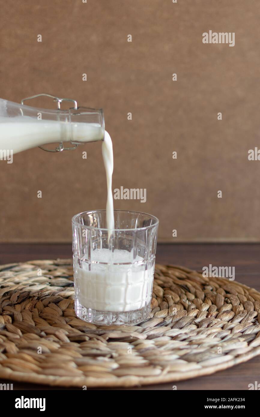 Gießen in Glas Milch aus einem Glas Flasche. Horizontale Ausrichtung. Stockfoto