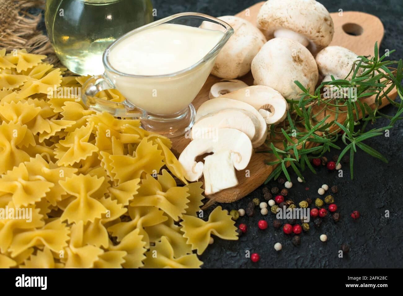 Zutaten für das Kochen von Nudeln mit Champignons in Sahnesauce auf schwarzem Hintergrund. Close-up. Stockfoto