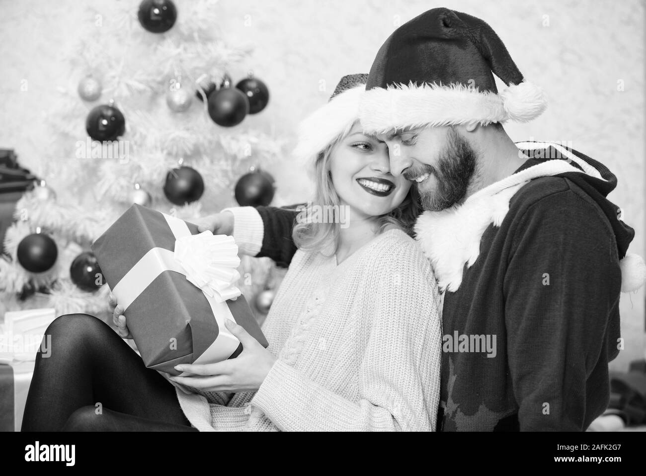 Feiern Weihnachten zusammen. Paar kuscheln Lächeln beim Auspacken der Geschenke mit Weihnachtsbaum Hintergrund. Weihnachten mit der Familie Tradition. Paar in der Liebe genießen Sie Weihnachten feiern. Stockfoto