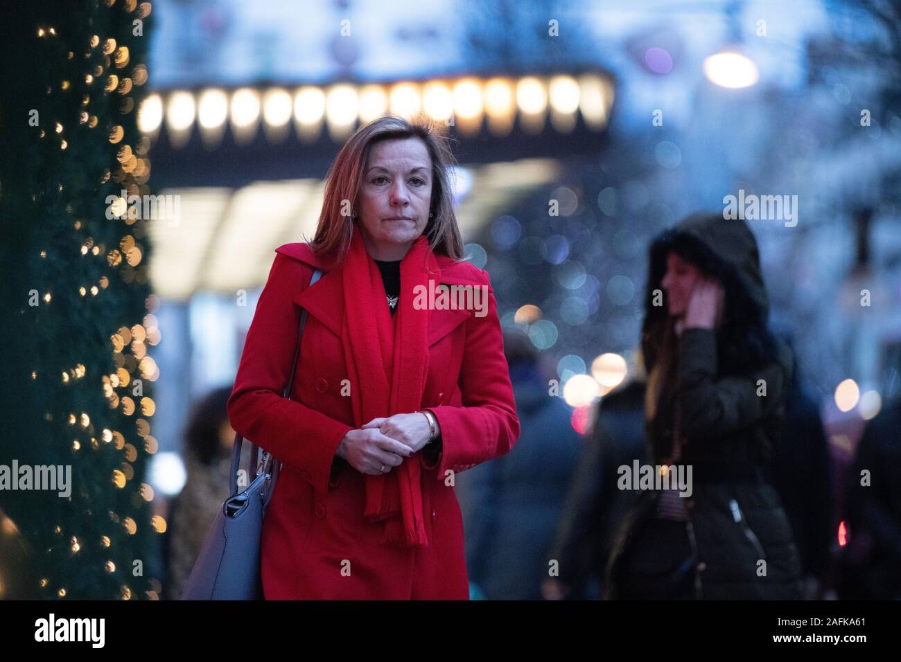 Eine Frau das Tragen der roten Mantel wandern, durch ihre Gedanken außerhalb Selfridges iconic Eingang belegt, Weihnachtsbeleuchtung, Oxford Street, London, UK Stockfoto