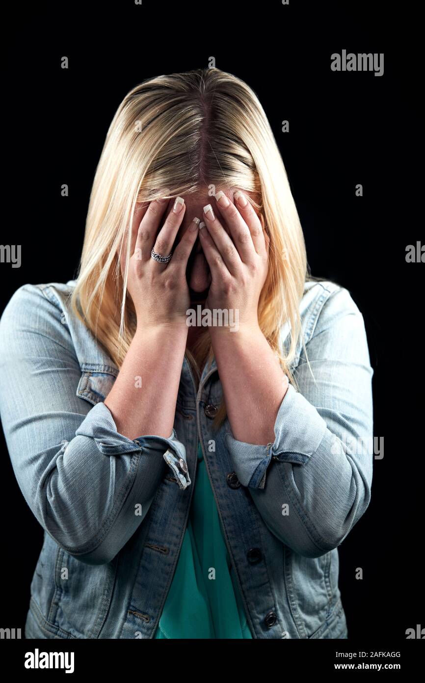 Studio Portrait von Schämen junge Frau mit Gesicht mit den Händen Stockfoto