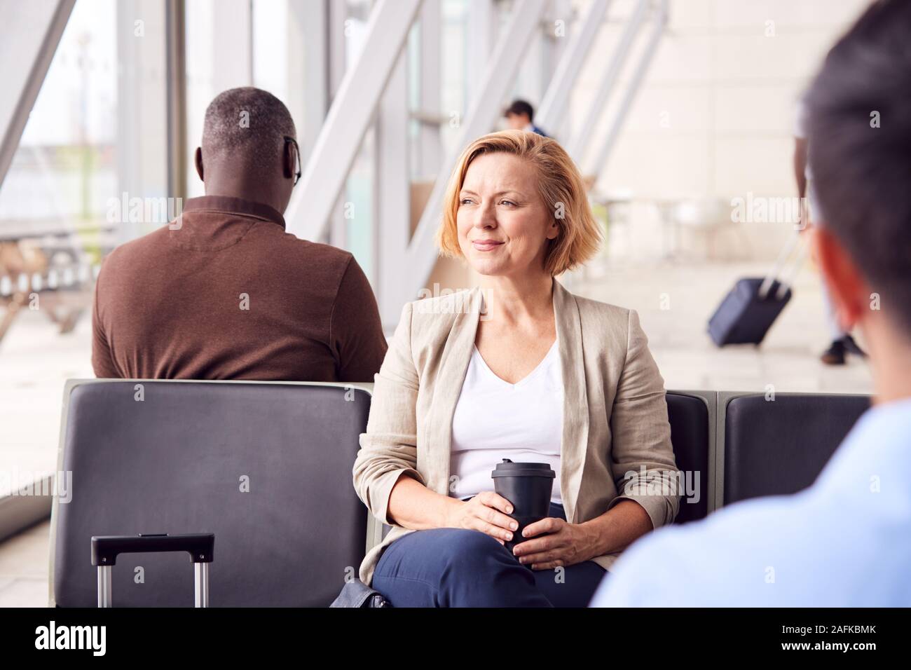 Reife Geschäftsfrau Warten im Flughafen Abflug Lounge trinken Kaffee aus wiederverwendbaren Schale Stockfoto