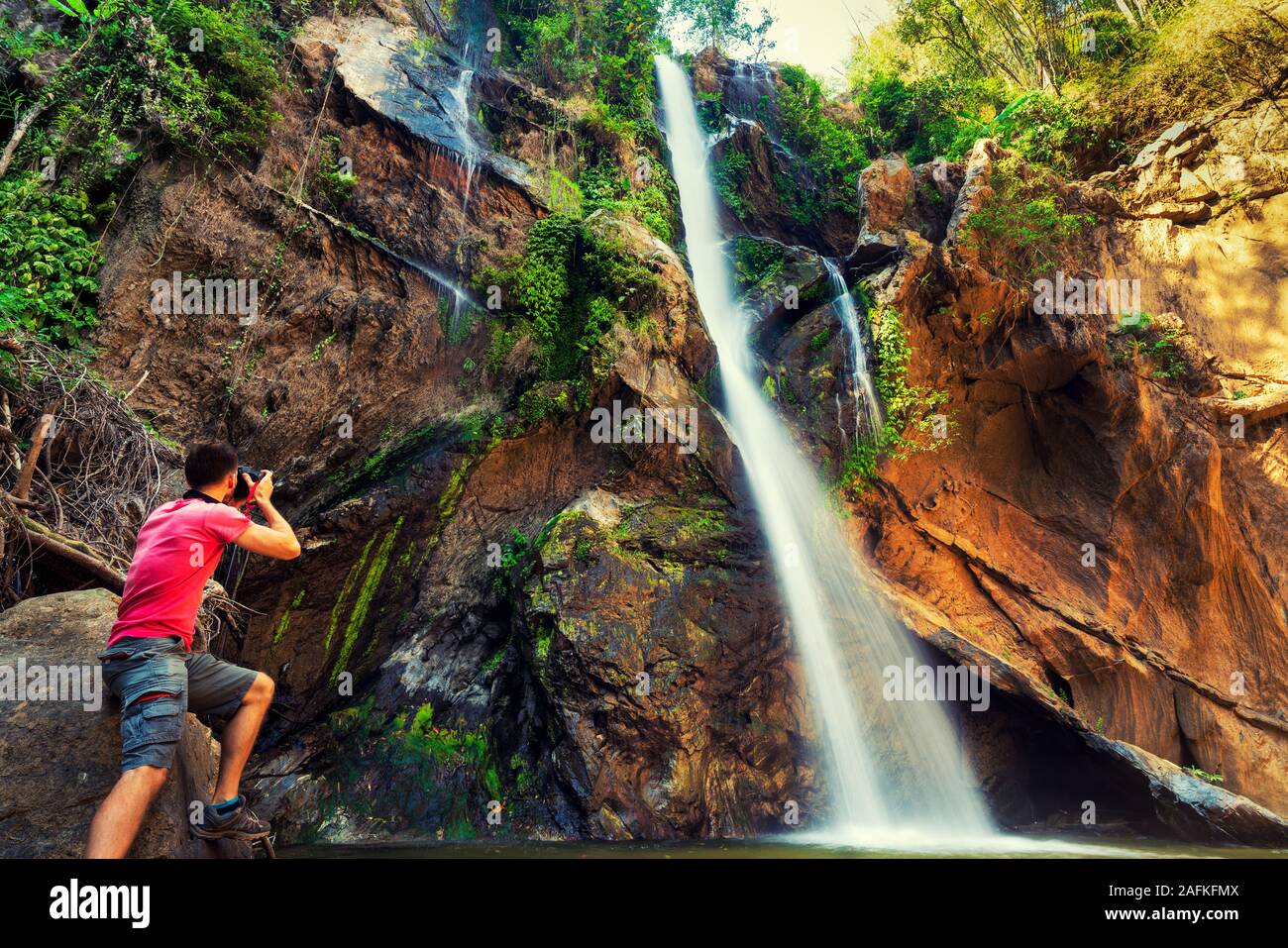 Reisender Fotograf machen Foto erstaunlicher tropischer Wasserfall versteckt im Regenwald. Reisen Lifestyle und Erfolgskonzept Ferien in die wilde Natur Stockfoto