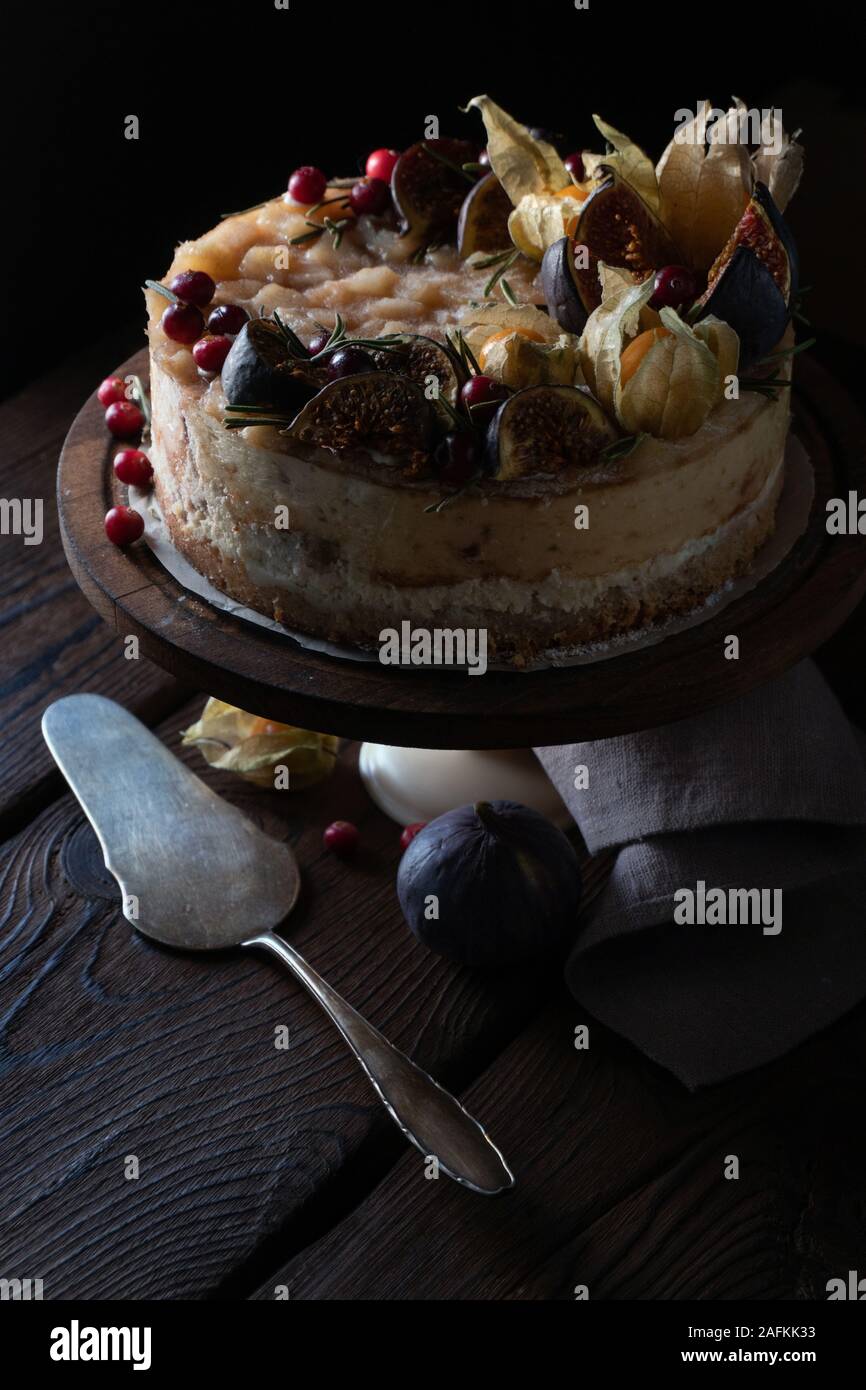 Käsekuchen mit Termine und Physalis auf Stativ mit einer Serviette und Löffel vertikal Stockfoto