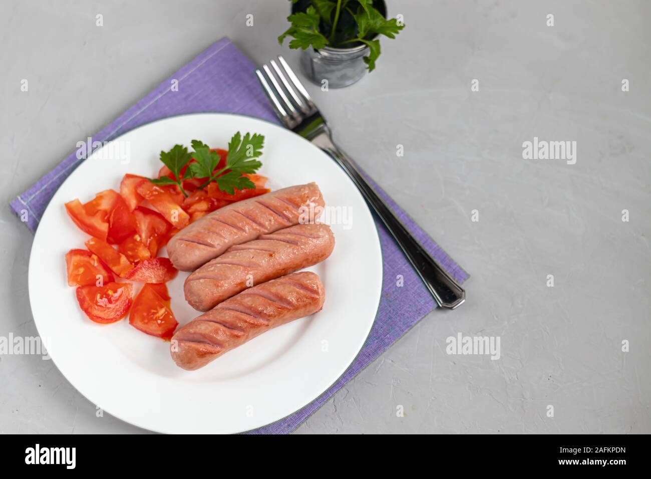Frühstück mit Würstchen und Gemüse. Tomaten in Scheiben geschnitten. Auf einem hellen Hintergrund. Stockfoto