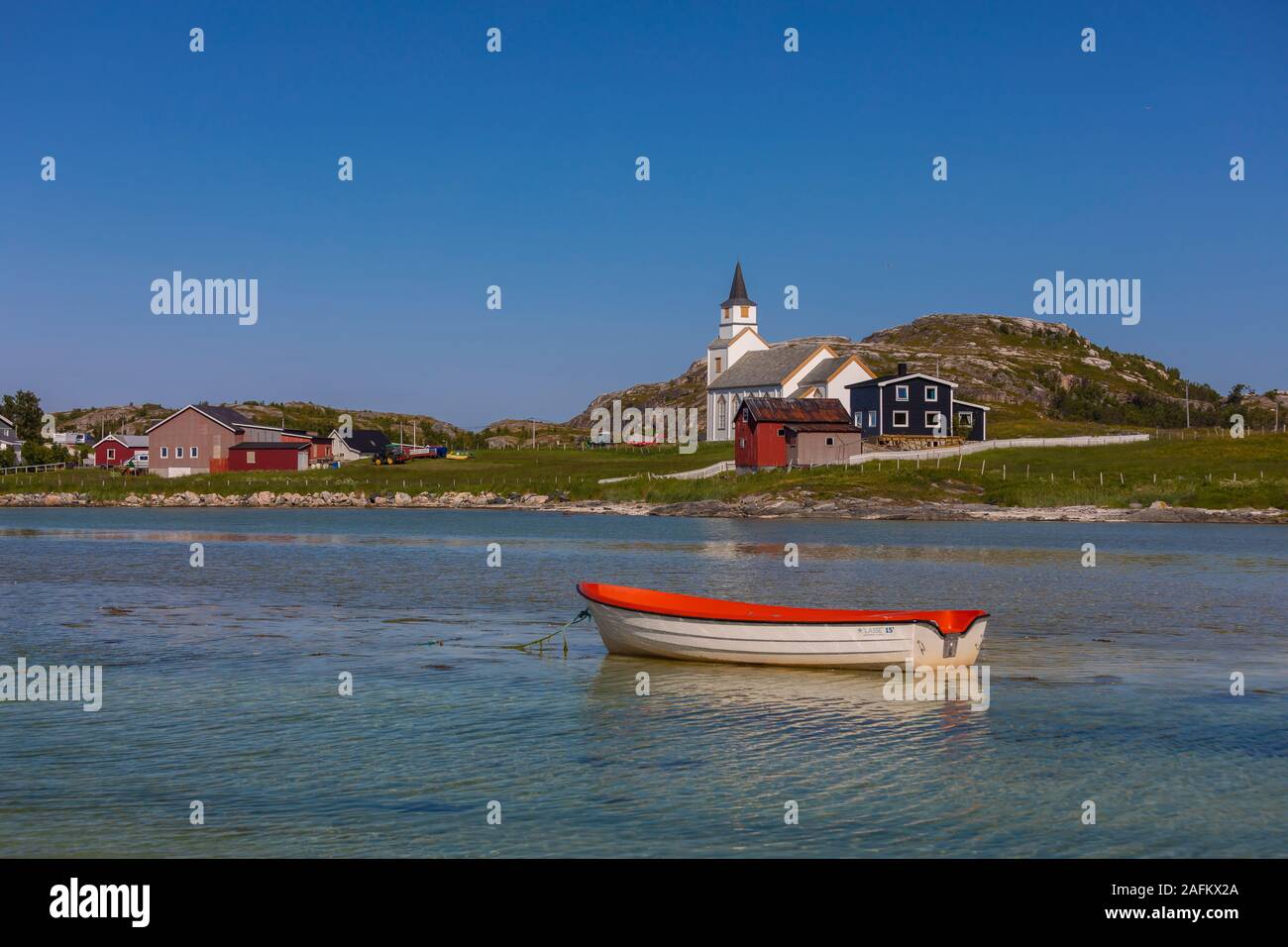 HILLESØY, Troms County, NORWEGEN - Kleines Boot auf dem Wasser vor Hillesøy Kirche im Norden Norwegens. Stockfoto