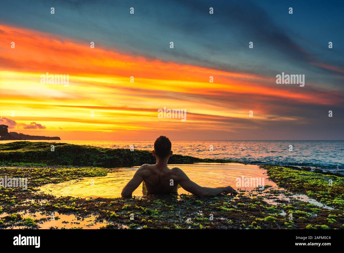 Silhouette Reisen Männer Genießen den Sonnenuntergang im Natürlichen Pool EINES Tropical Beach Stockfoto