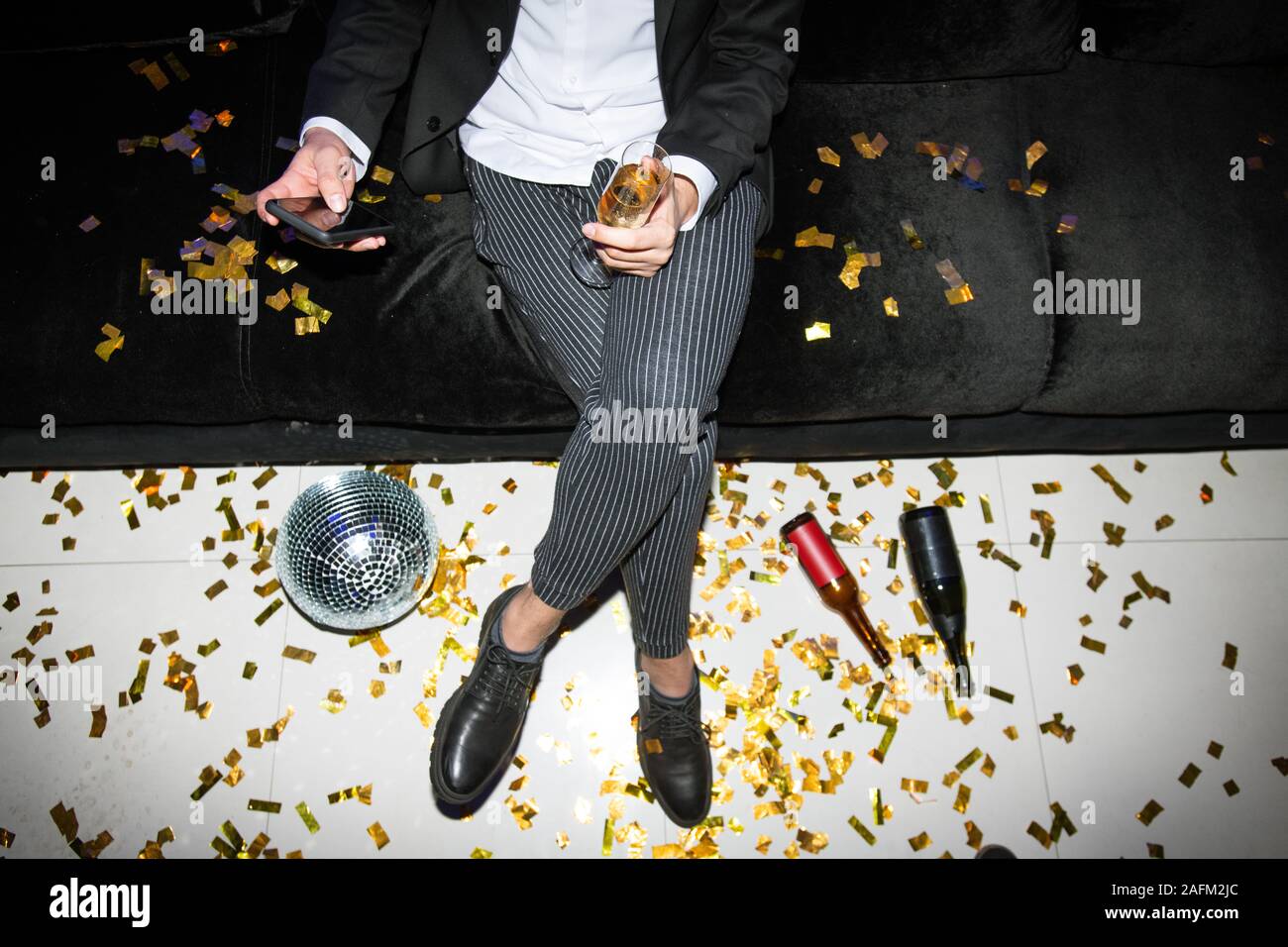 Niedrige Abschnitt der Jungen eleganten Mann mit Smartphone und Glas Champagner Stockfoto