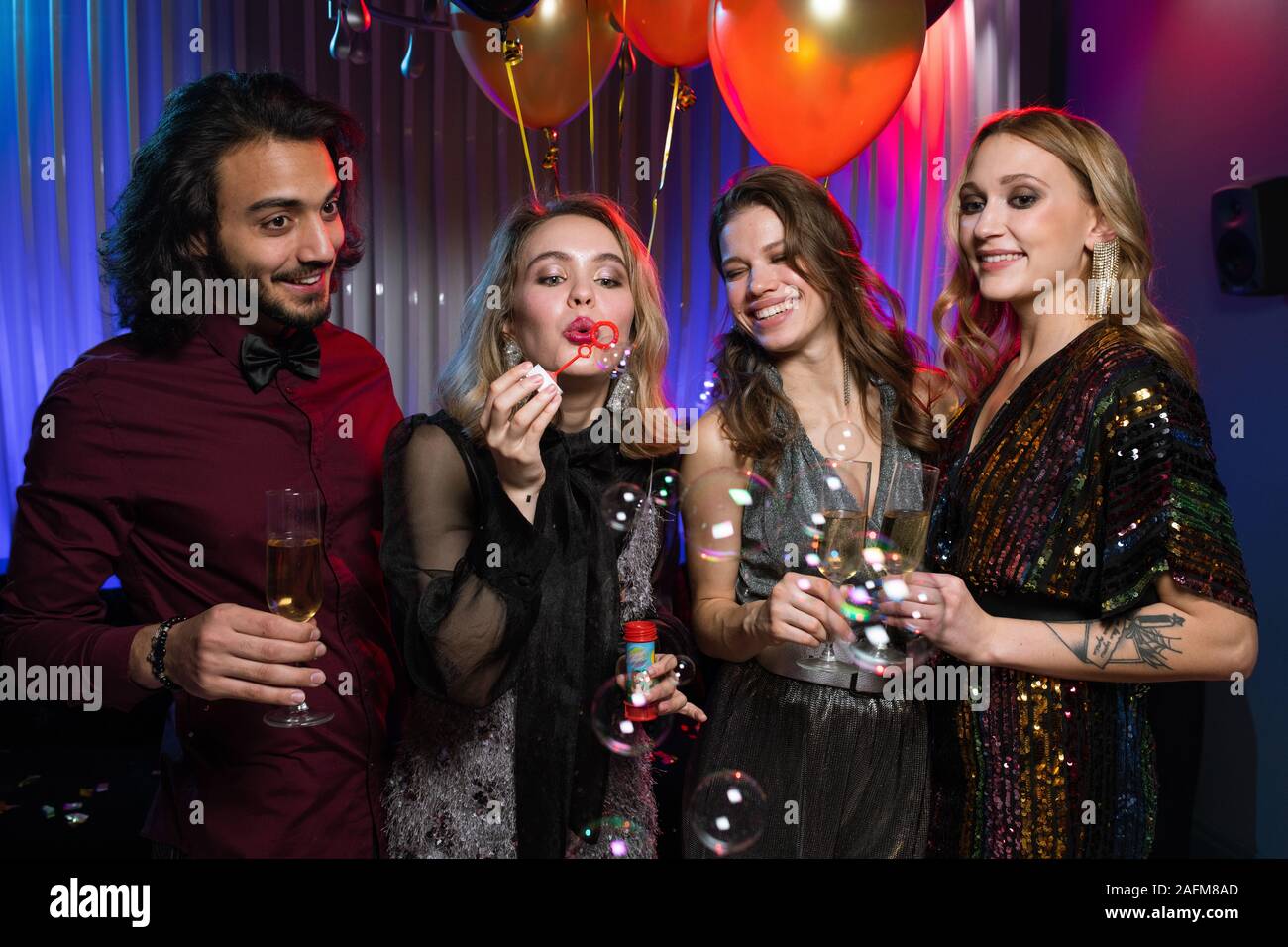 Eine der hübschen Mädchen bläst Seifenblasen unter Ihren Freunden bei Geburtstagsfeier Stockfoto