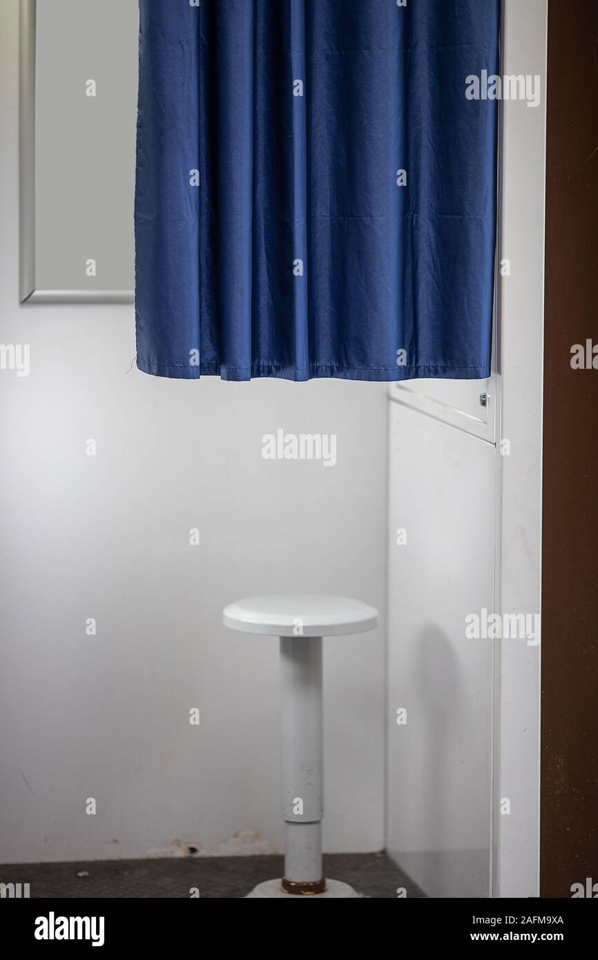 Alte weiße Drehstuhl in einem passfoto Kabine, halbe Länge blauen Vorhang für Datenschutz Stockfoto