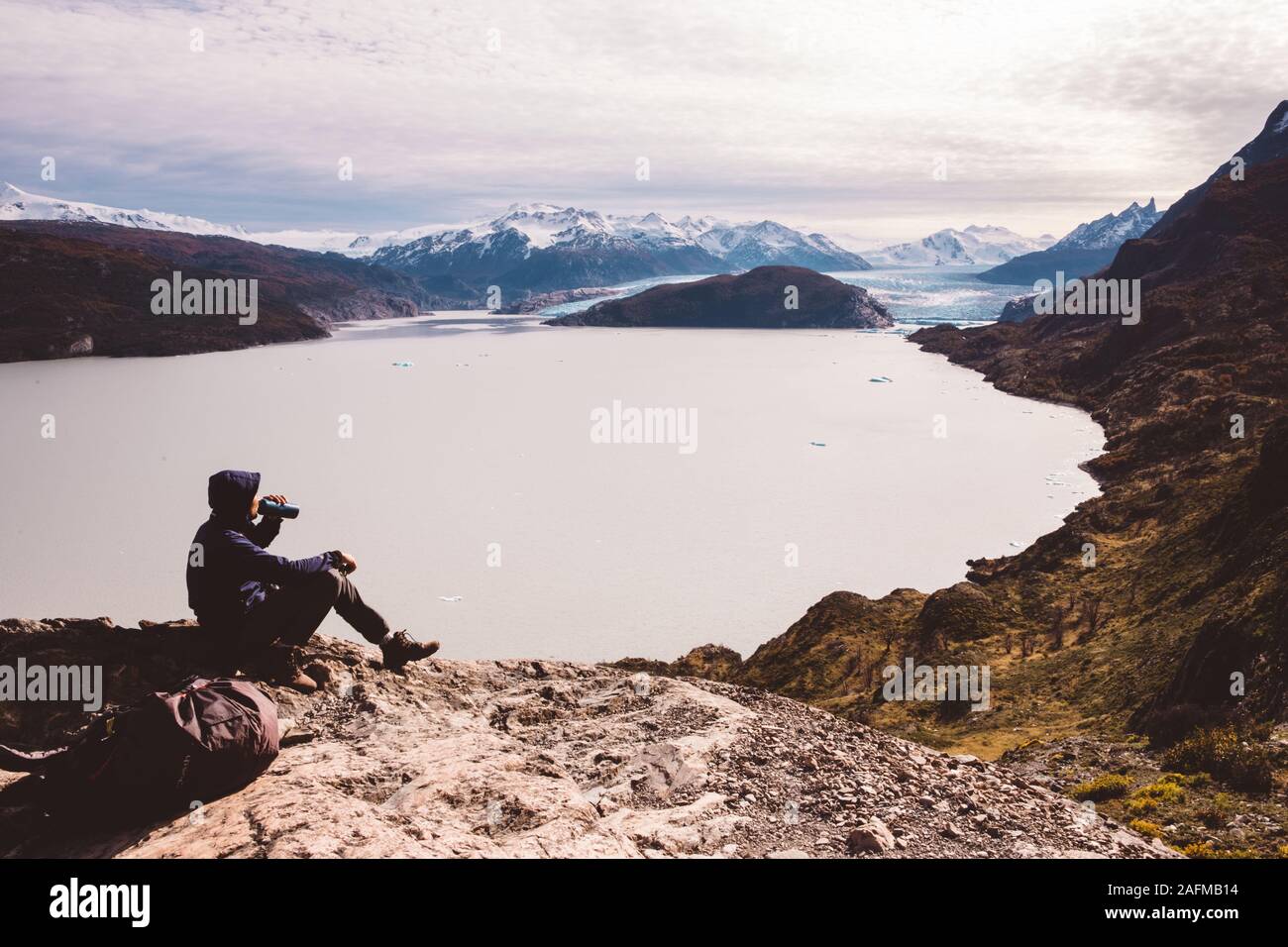 Mann das Trinken aus einer Flasche am Rock am See mit Gletschern Stockfoto