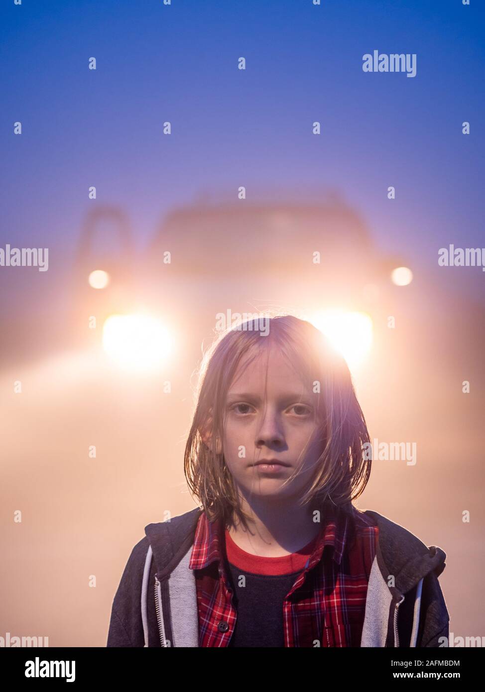 Portrait von Tween mit schulterlanges Haar durch Scheinwerfer mit Hintergrundbeleuchtung Stockfoto