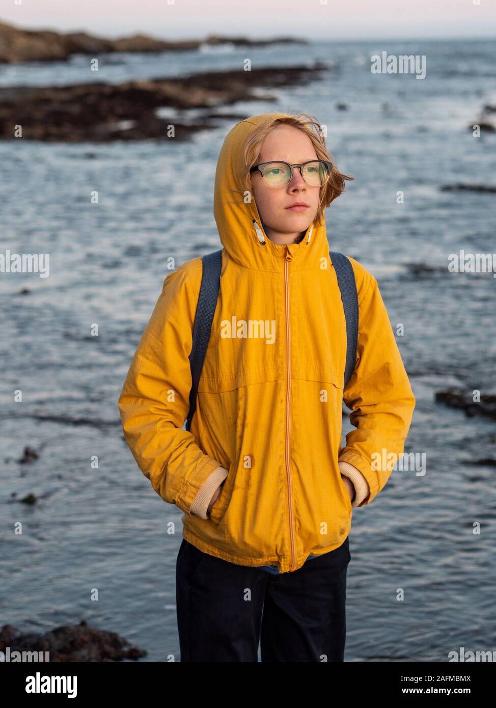 Taille bis Portrait von Tween beobachten Sonnenuntergang auf felsigen Ufer Stockfoto