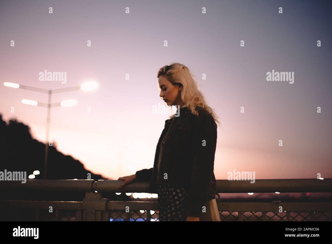 Junge Frau auf der Brücke gegen Himmel bei Sonnenuntergang Stockfoto