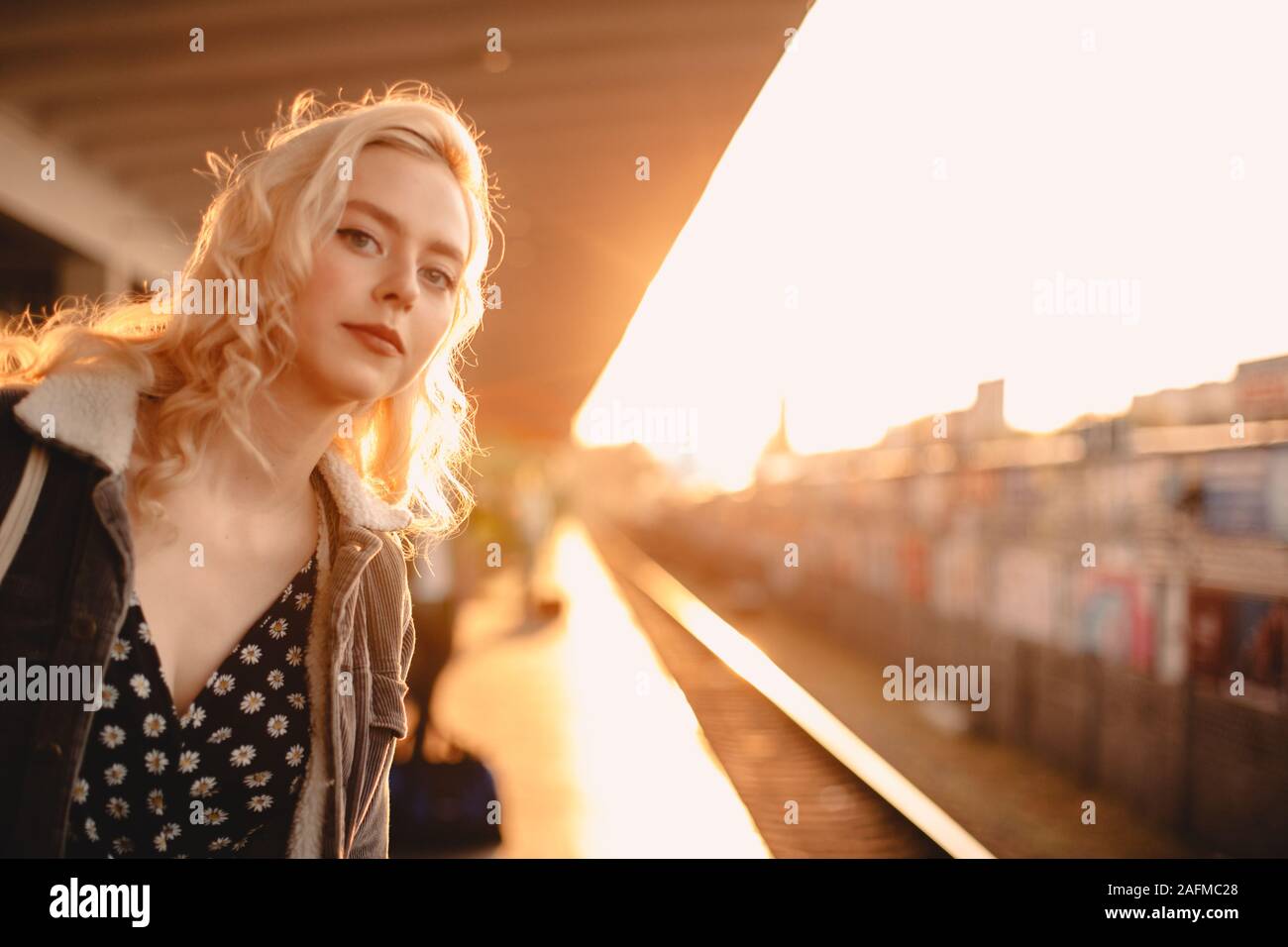 Junge Frau wartet auf Zug in der Nähe der U-Bahn Station bei Sonnenuntergang Stockfoto