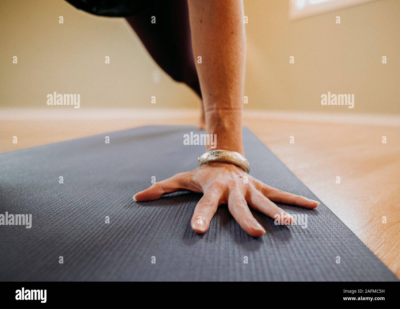 Nahaufnahme eines weiblichen Hand mit Armband auf eine Yogamatte in einem Studio Stockfoto