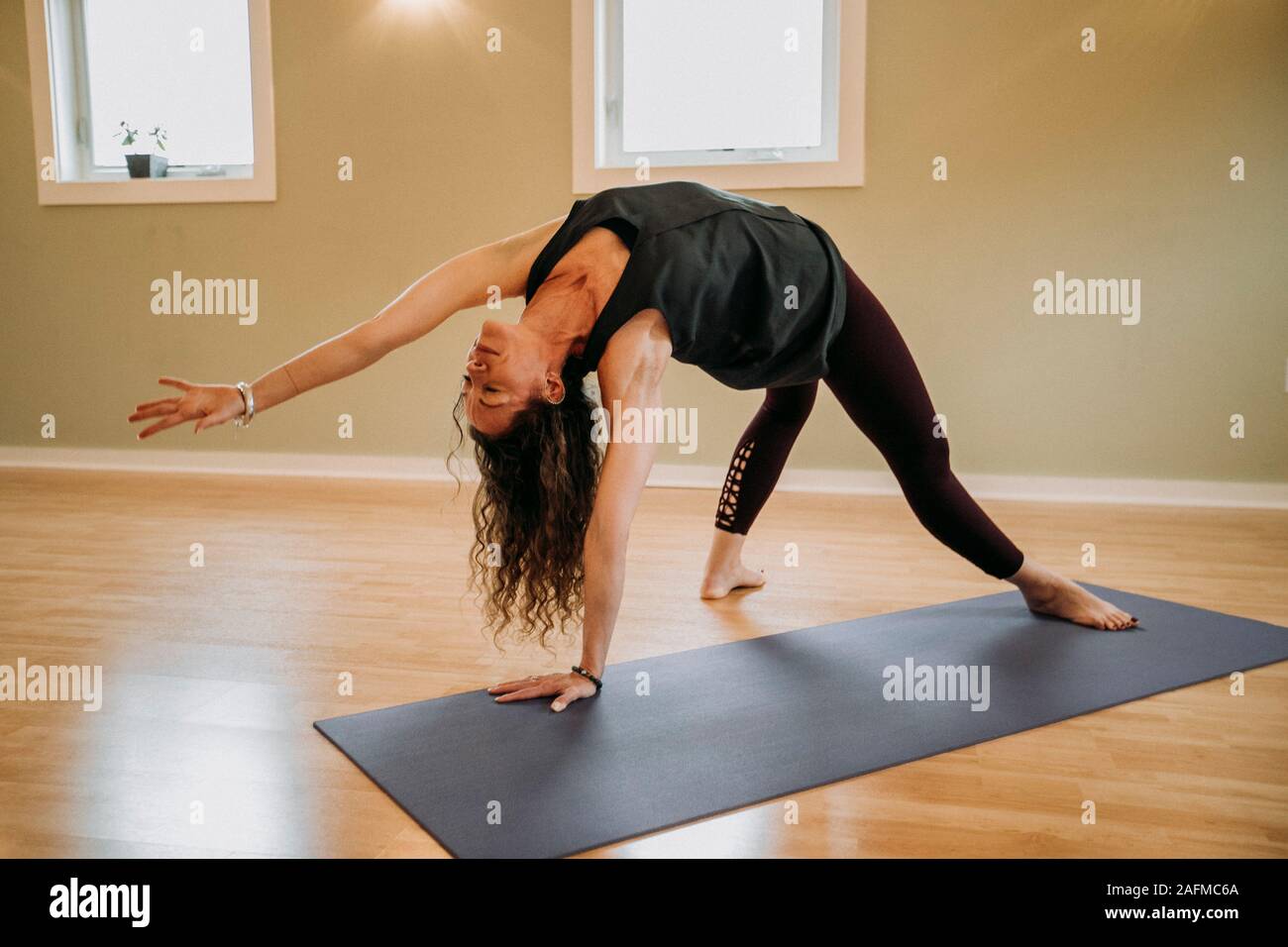 Frau mit schwarzen übt Yoga auf einer Matte in einem Studio Stockfoto