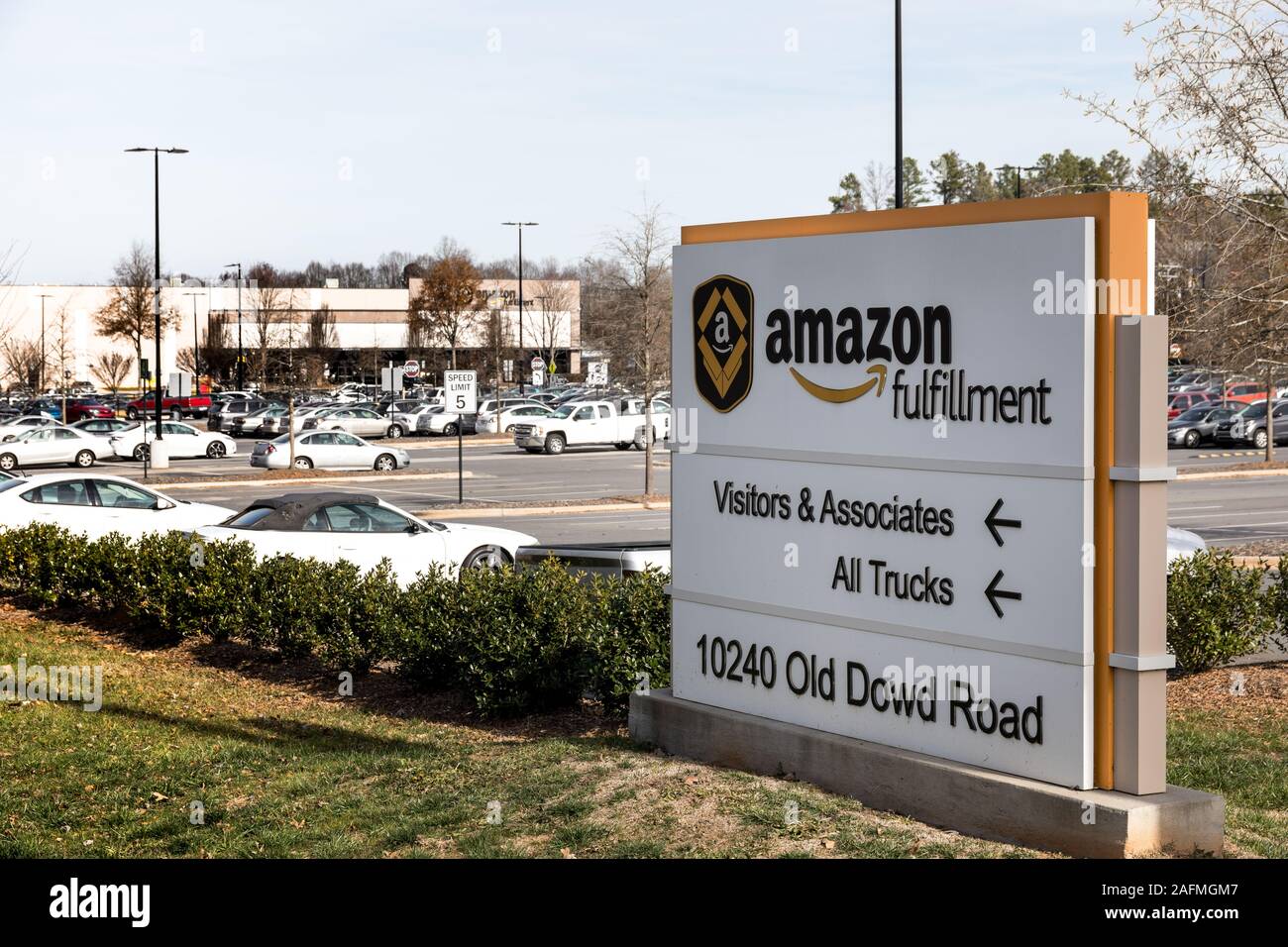 CHARLOTTE, NC, USA-8 Dezember 2019: Ein Amazon Fulfillment Center und Straßenschild auf Wilkinson Blvd., mit Parkplatz voller Mitarbeiter Fahrzeuge. Stockfoto