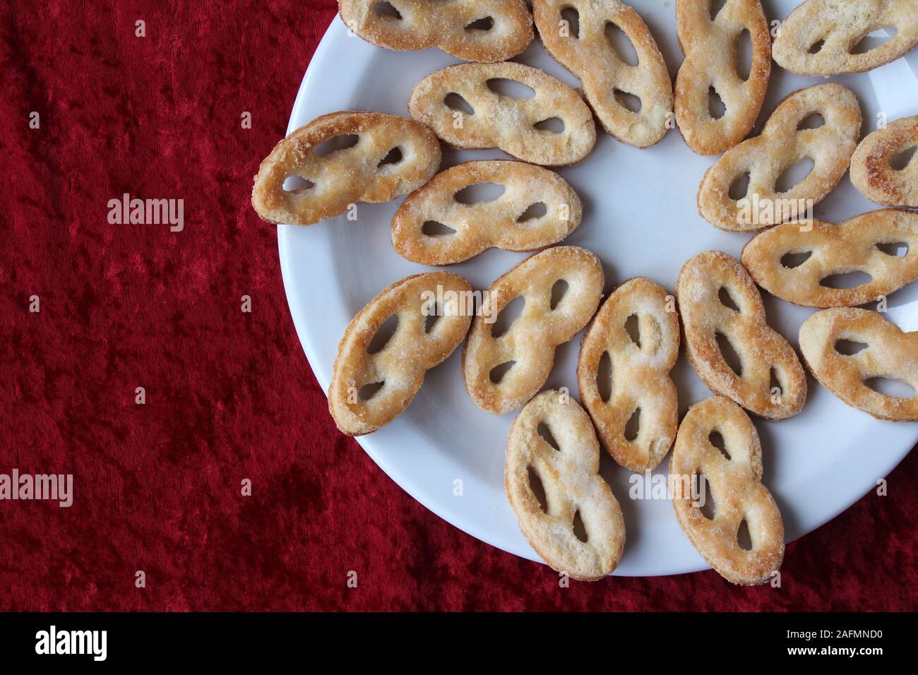Flach auf eine weiße Platte mit einem gefüllten krakeling" eine sehr beliebte Art der Niederländischen Cookie. Rot Tischdecke Hintergrund und Kopieren auf der linken Seite. Stockfoto