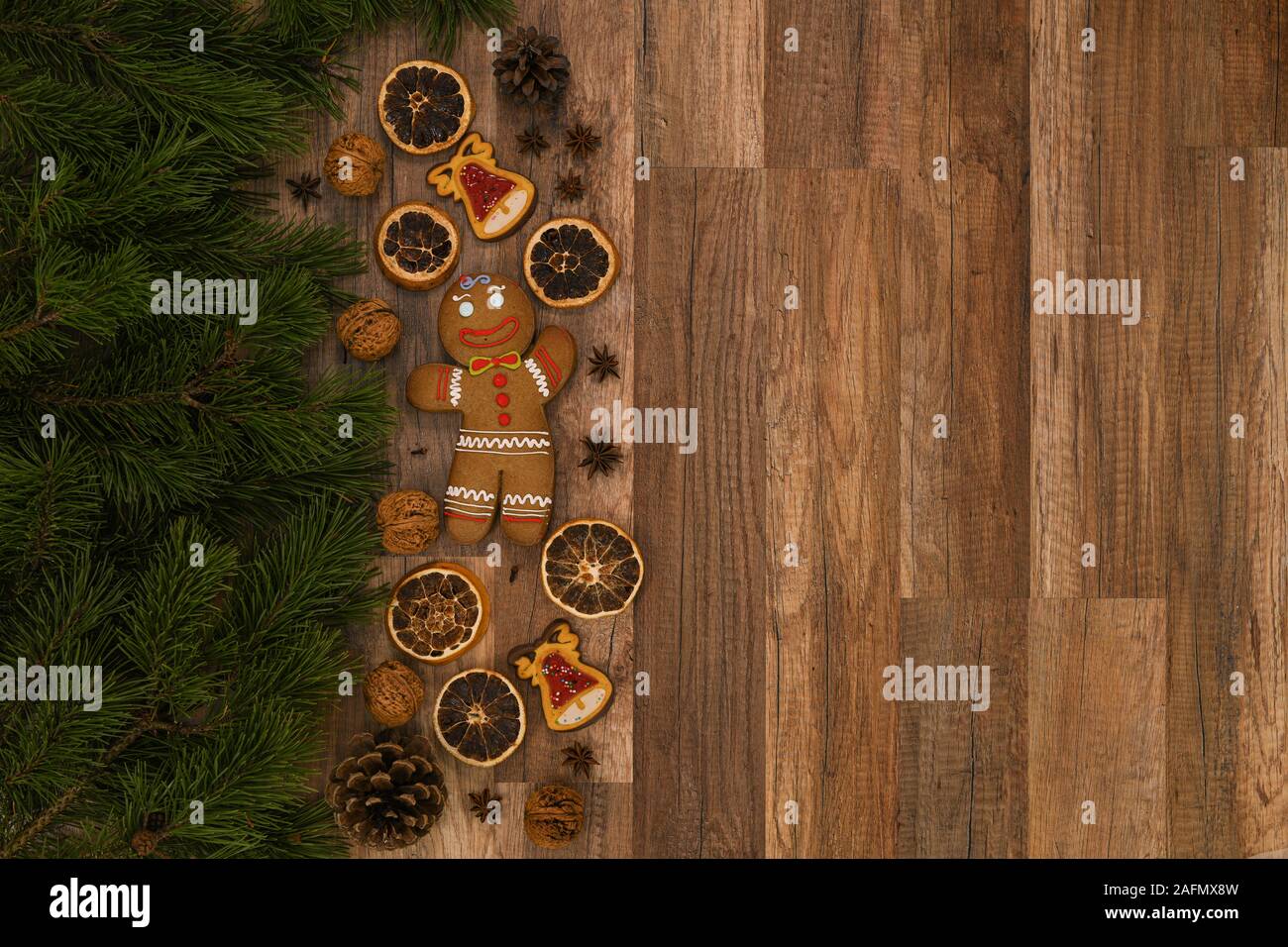 Weihnachtskarte mit Tanne und Ingwerbrot auf rustikalem Holzhintergrund. Stockfoto