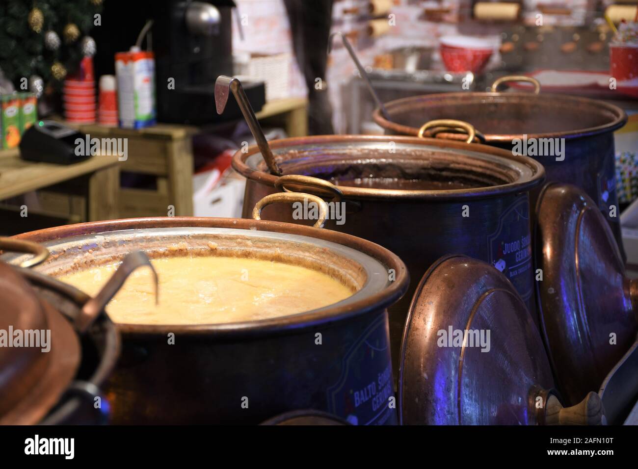 Heiße weiße und dunkle Schokolade in einem großen Kupfertopf in einem Weihnachtsmarkt, bereit zu essen, Street Food im Winter, Markt wegen Covid abgesagt Stockfoto