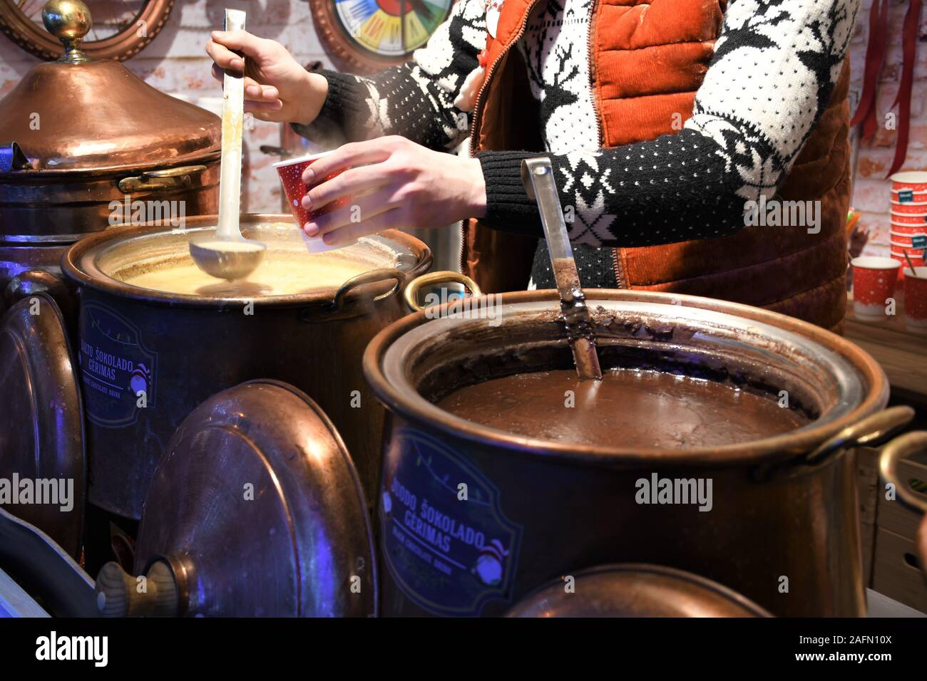 Heiße weiße und dunkle Schokolade in einem großen Kupfertopf in einem Weihnachtsmarkt, bereit zu essen, Street Food im Winter, Markt wegen Covid abgesagt Stockfoto