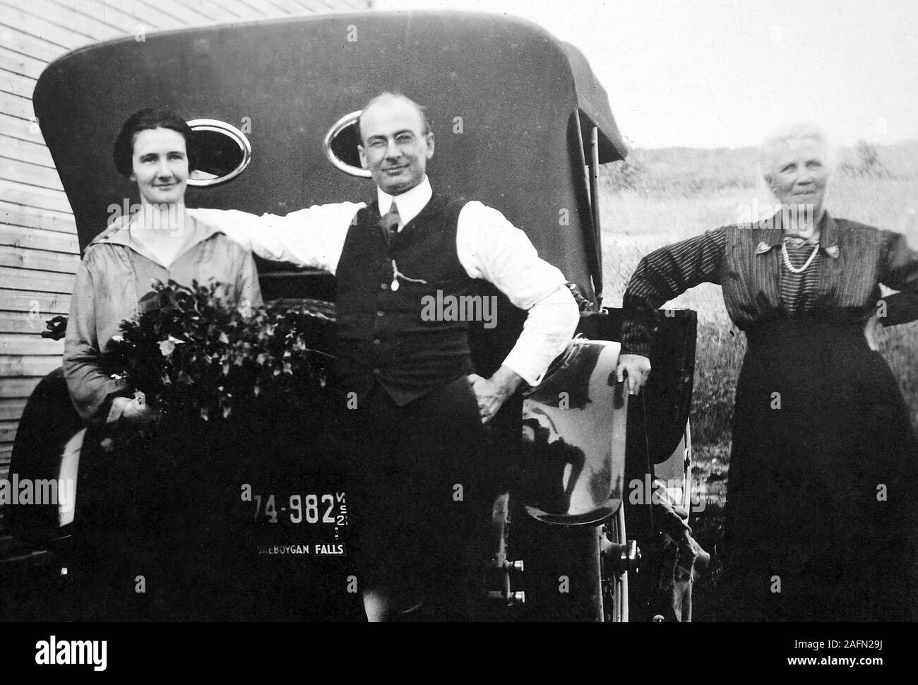 Die Schwiegermutter stellt auf der einen Seite mit Tochter und Schwiegersohn neben dem neuen Auto in Wisconsin, Ca. 1925. Stockfoto