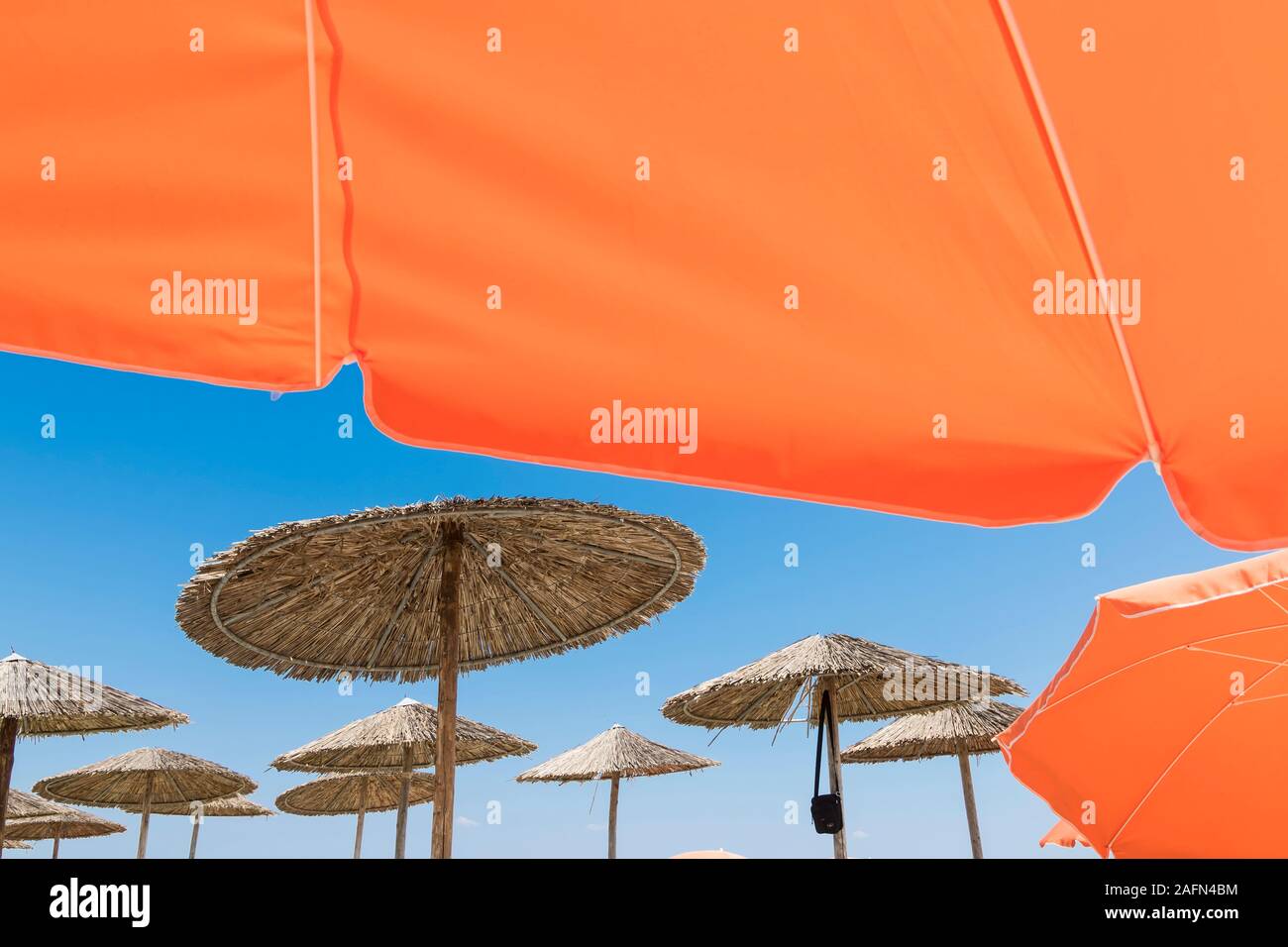 Wicker und Textil orange Sonnenschirme am Strand. Blue Sky. Stockfoto