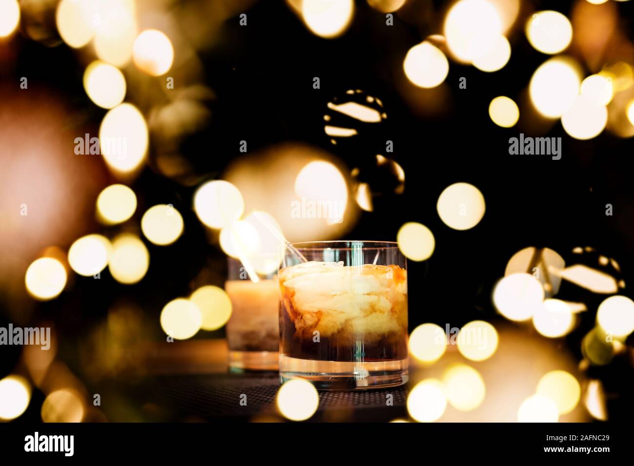Zwei White Russian Cocktails an der Bar stehen auf Gummimatte. Flache DOF und Marsala tonned mit festlichen Bokeh leuchtet Stockfoto