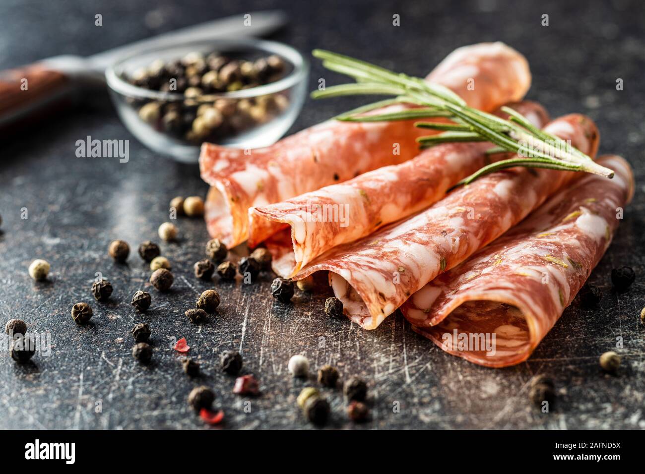 Salami in Scheiben geschnitten. Wurst Fleisch mit Pfeffer und Rosmarin. Stockfoto