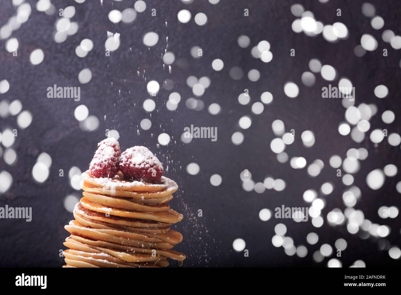 Stapel Pfannkuchen mit Himbeeren auf der Oberseite. Hausgemachte Desserts. Maslenitsa Konzept. Dunkel grau hinterlegt. Sichten Pulver Zucker. Horizontale und einige Bokeh Stockfoto
