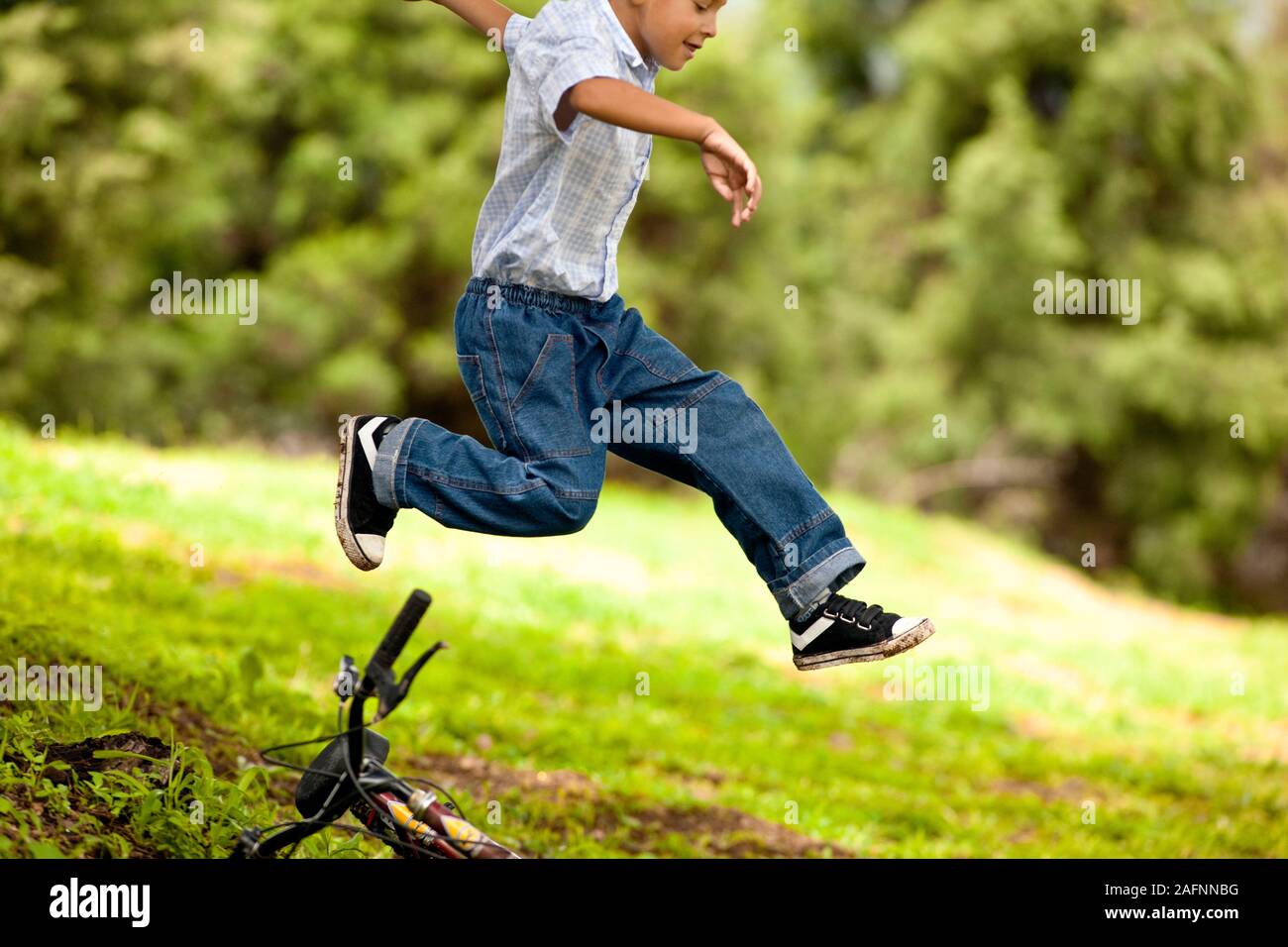 Junge über sein Fahrrad auf dem Hügel springen. Stockfoto