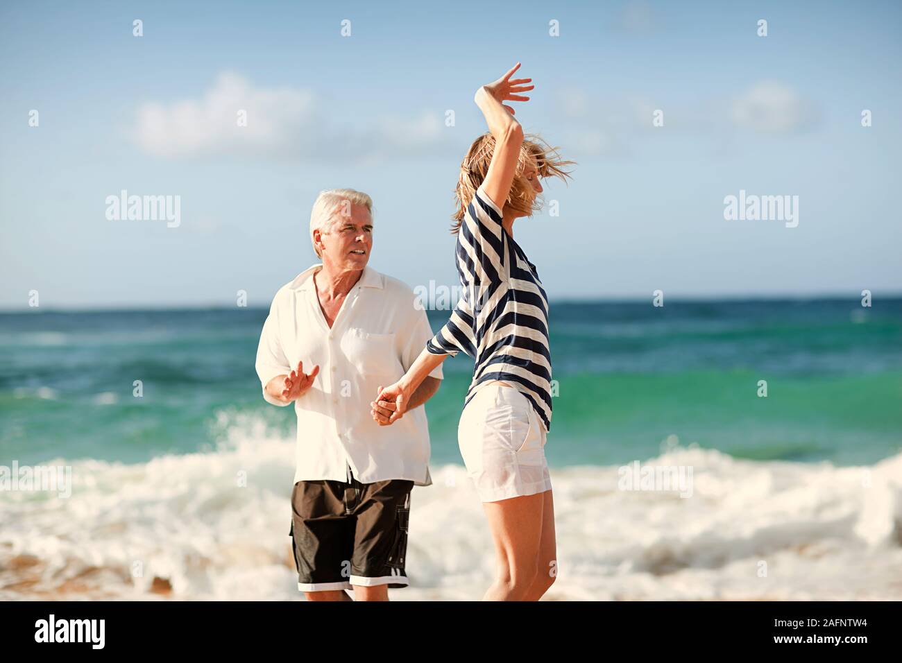 Mitte der erwachsenen Frau tanzen mit ihrem Mann am Strand. Stockfoto
