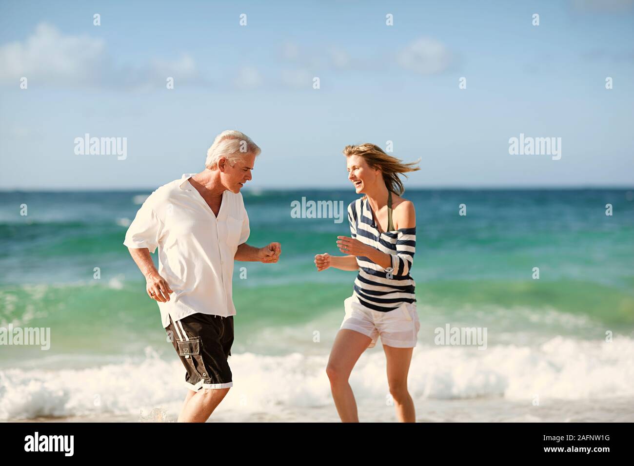Mitte der erwachsenen Frau tanzen mit ihrem Mann am Strand. Stockfoto