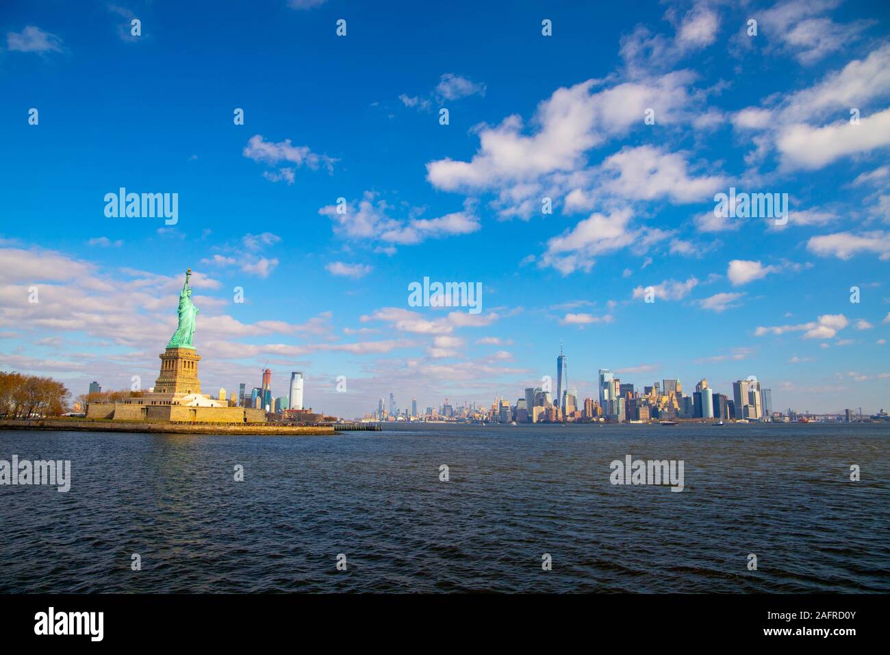 Die Freiheitsstatue und die Skyline von New York isoliert auf den blauen Himmel mit weißen Wolken. Oktober 11,2018 Stockfoto