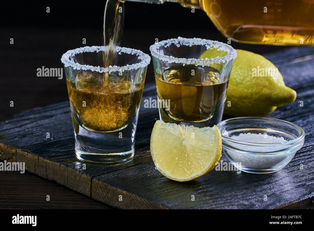 Starke alkoholische Getränk ist in einem Glas auf Holz- Hintergrund gegossen Stockfoto