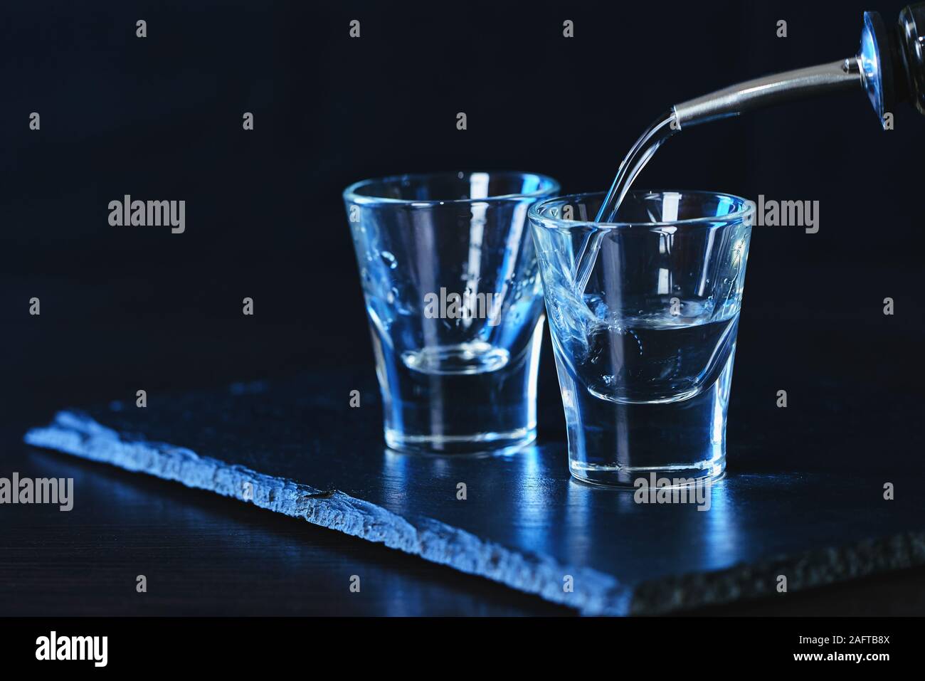 Flasche Wodka in ein Glas auf einem dunklen Hintergrund gegossen Stockfoto